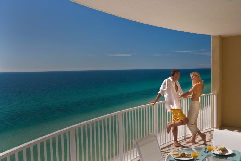 couple standing on balcony overlooking gulf of mexico